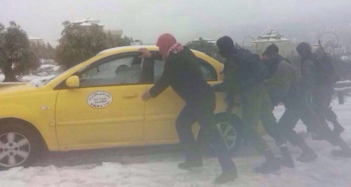 Israelische Soldaten helfen einem palästinensischen Taxifahrer aus dem Schneematsch.