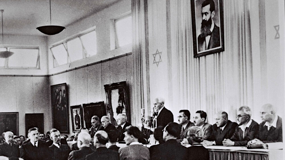 David Ben-Gurion verliest im Stadtmuseum von Tel Aviv die israelische Unabhängigkeitserklärung – über ihm ein Portrait von Theodor Herzl, dem Begründer des modernen Zionismus