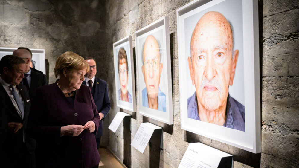 Mahnende Bilder: Bundeskanzlerin Merkel betrachtet die Portraits der Ausstellung „Survivors“