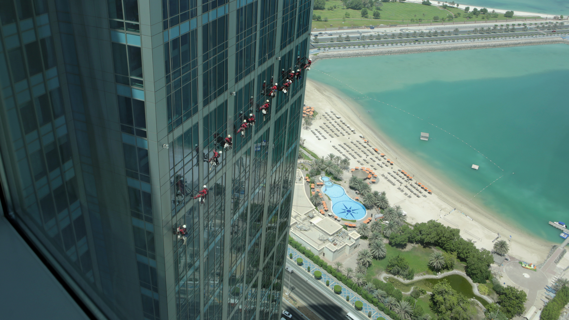 In den frühen Morgenstunden putzen Gastarbeiter die Fenster eines Hotels in Abu Dhabi