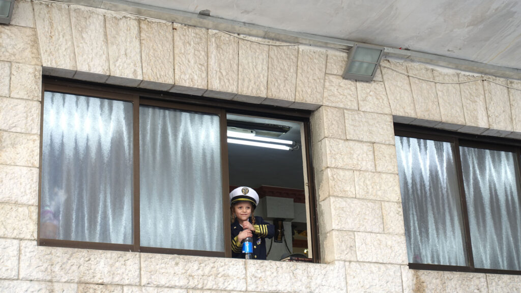 ein als Polizist verkleideter Junge in einem Fenster feiert Purim