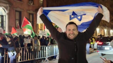 Comedian Guy Hochman mit Israel-Flagge vor pro-palästinensischen Demonstranten